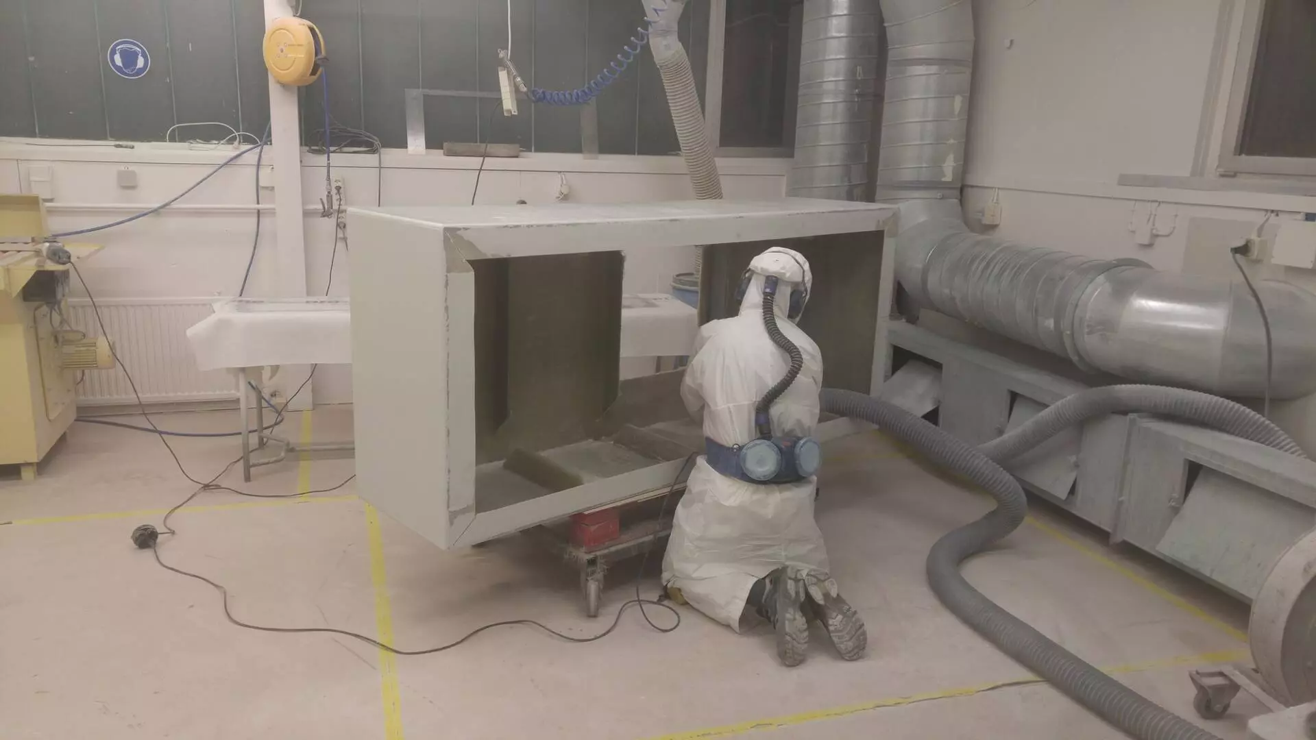 GFK-Tank in der Produktion Mitarbeiter in Schutzanzug bearbeitet einen GFK-Tank in der Produktion